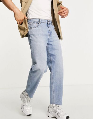 Jeans comodi affusolati lavaggio chiaro con fondo grezzo-Blu - ASOS DESIGN - Modalova